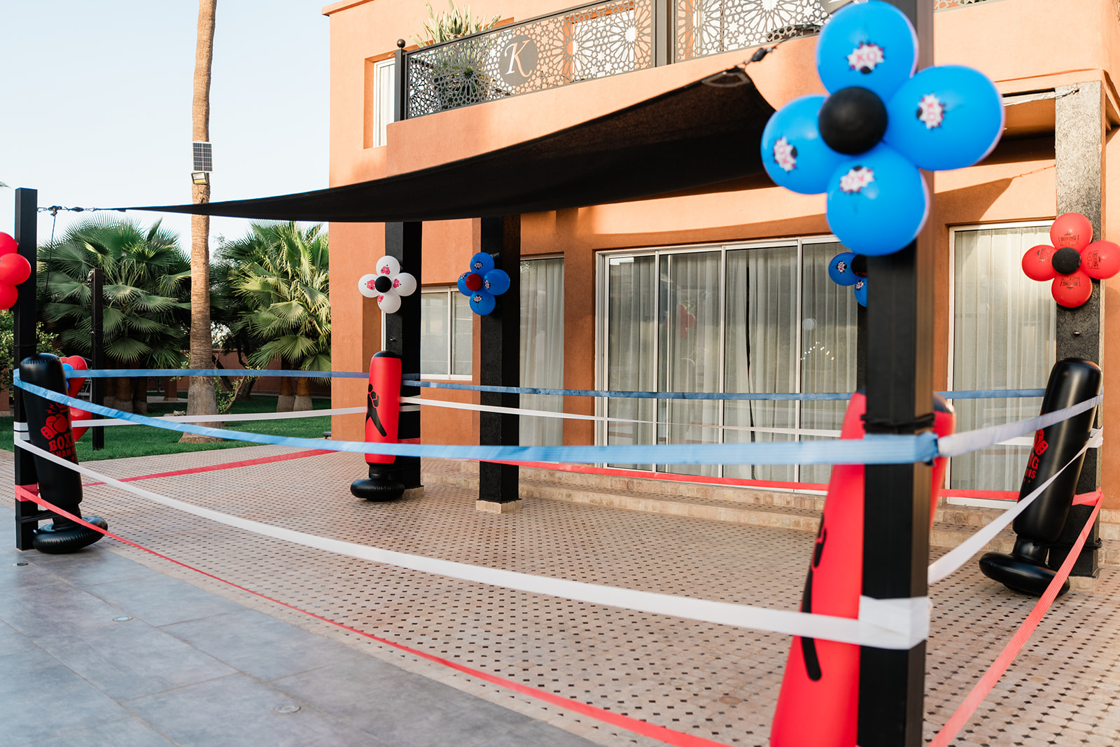Espace photo à thème sportif avec ring de boxe décoré de ballons et éclairage coloré